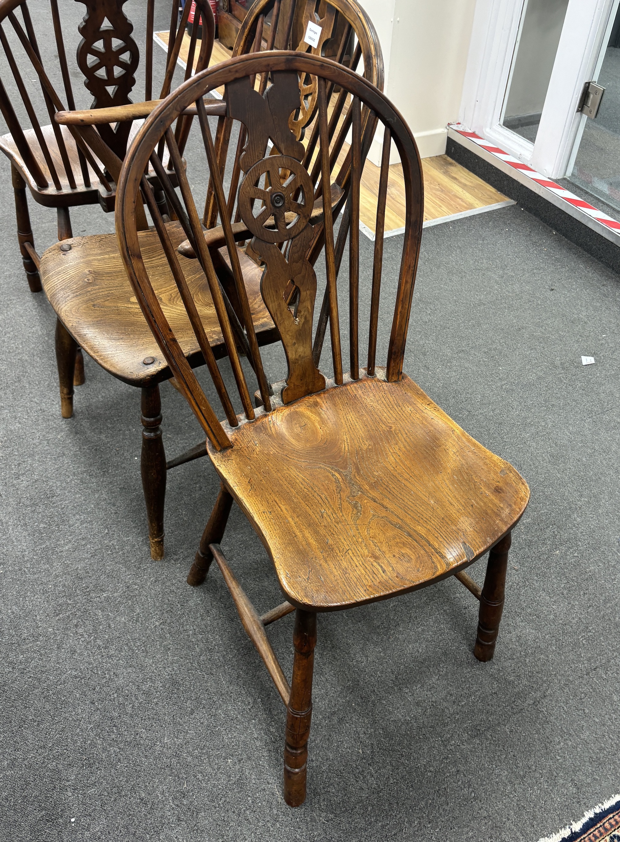A set of three mid 19th century elm and ash wheel back dining chairs, one with arms